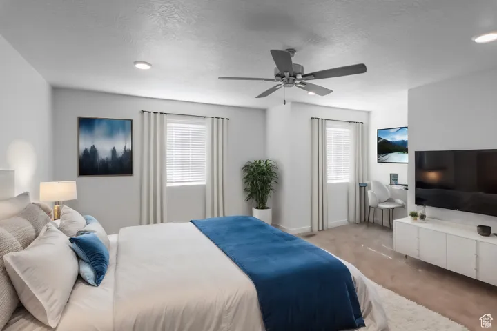 Bedroom featuring carpet flooring, multiple windows and a ceiling fan