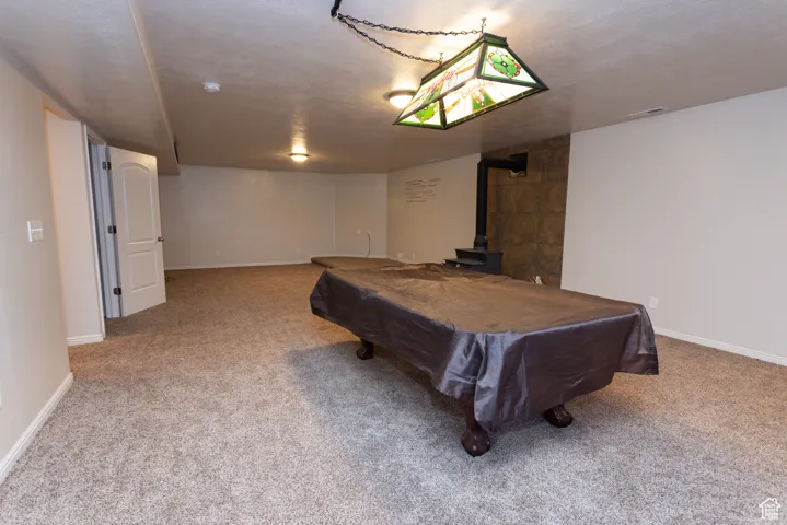 Playroom featuring a wood stove, billiards table, light colored carpet, and a textured ceiling