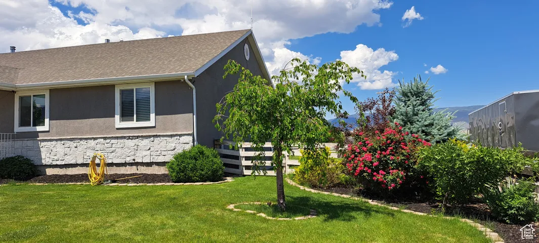 View of property exterior featuring stone siding, stucco siding, and a yard