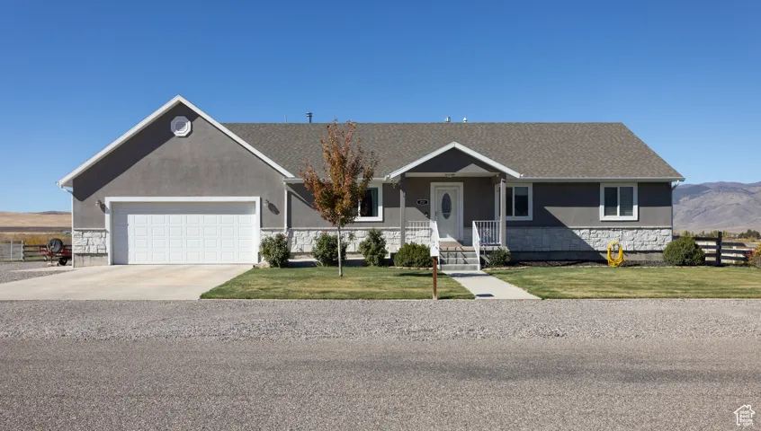 Single story home with stone siding, a front lawn, concrete driveway, and a garage