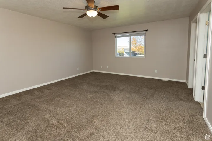 Unfurnished bedroom with dark carpet, a textured ceiling, and ceiling fan