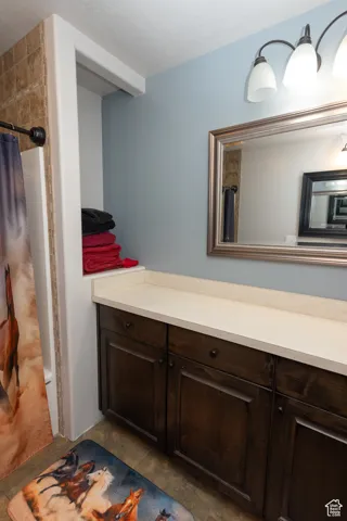 Full bath featuring curtained shower, tile patterned floors, and vanity