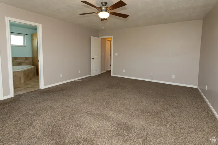Unfurnished bedroom with a textured ceiling, carpet floors, a ceiling fan, and ensuite bathroom