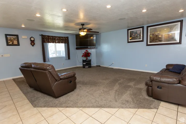 Living room featuring recessed lighting, a textured ceiling, light tile patterned flooring, ceiling fan, and light carpet