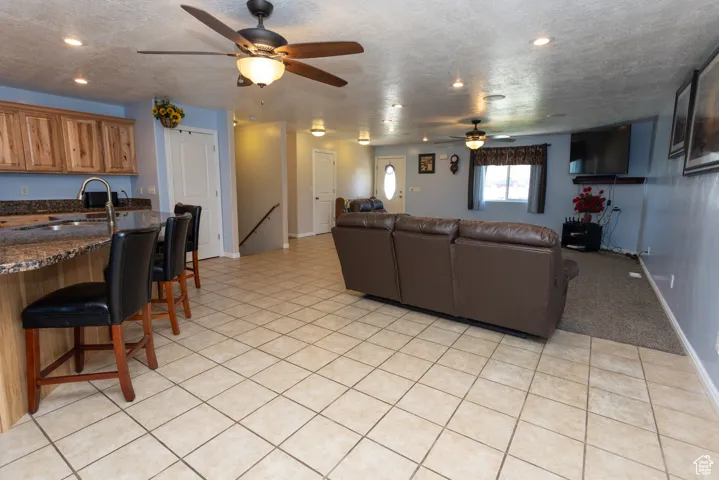 Living room with a textured ceiling, light tile patterned flooring, ceiling fan, and recessed lighting