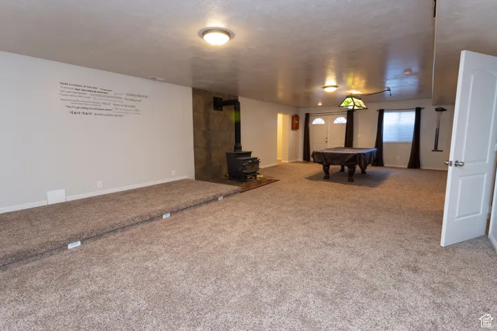 Playroom with a wood stove, pool table, carpet floors, and a textured ceiling