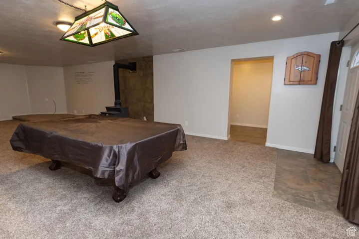 Recreation room with a wood stove, billiards table, light colored carpet, and a textured ceiling