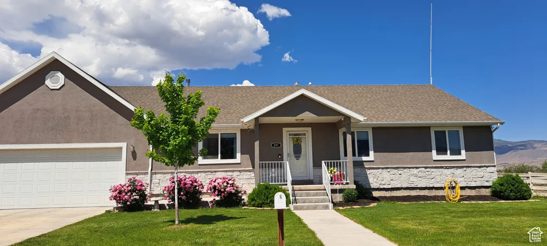 Ranch-style home with stone siding, a front lawn, stucco siding, a porch, and driveway