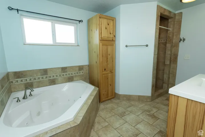 Full bath featuring vanity, a tub with jets, and a walk in shower