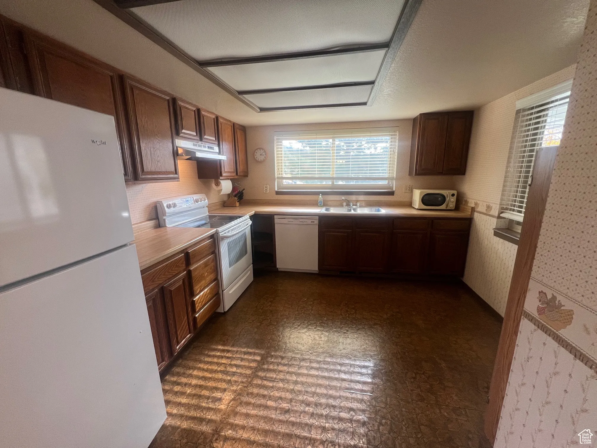 Kitchen with white appliances, light countertops, and under cabinet range hood