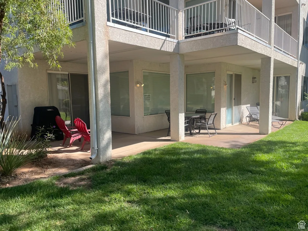 Rear view of property featuring a patio area, a balcony, stucco siding, and a yard