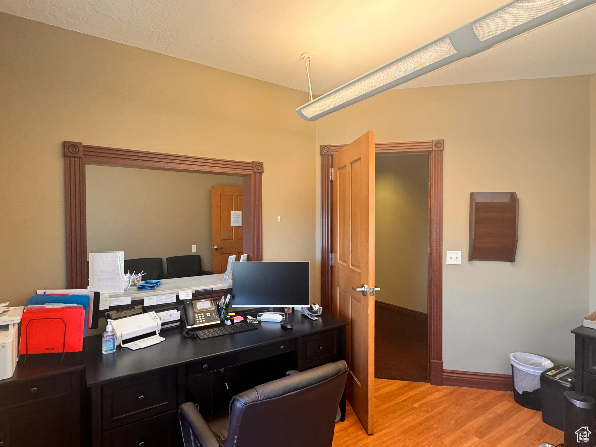 Office with light wood-type flooring and a textured ceiling