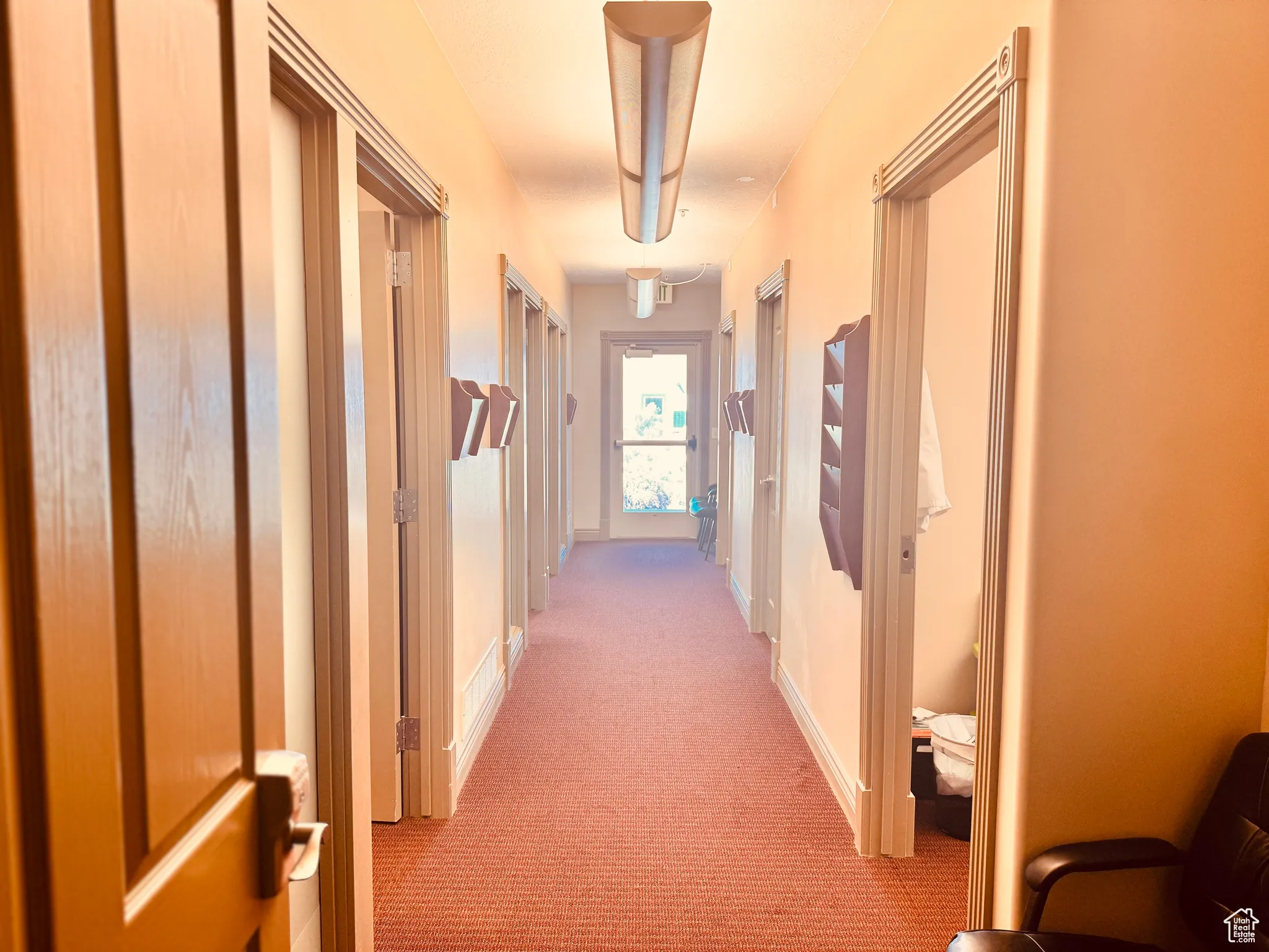 Hallway featuring light colored carpet and baseboards