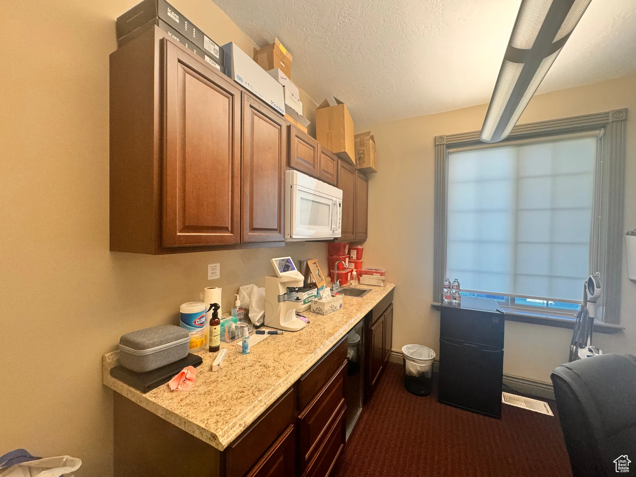 Kitchen featuring light countertops, white microwave, and a textured ceiling