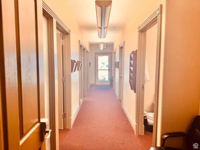 Hallway featuring light colored carpet and baseboards
