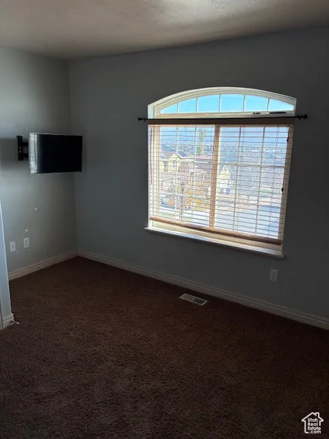 Empty room featuring dark carpet