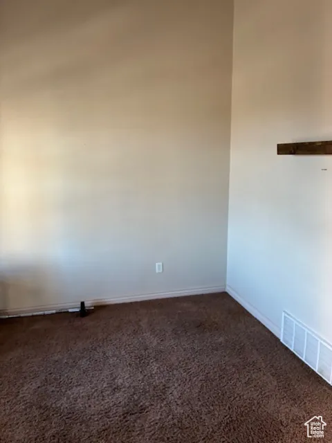 Unfurnished room featuring dark carpet and baseboards