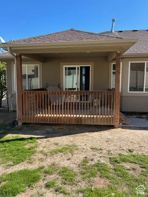 Back of house with stucco siding and roof with shingles