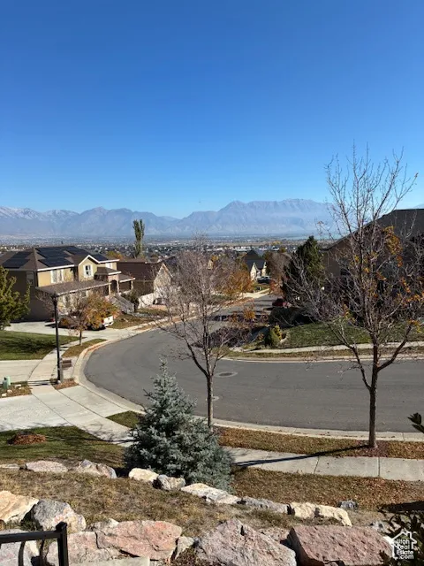 View of asphalt road featuring sidewalks, a mountain view, a residential view, and curbs