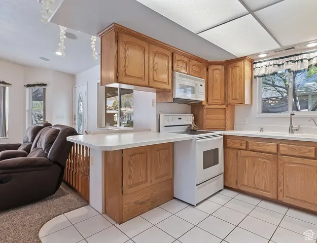 Kitchen with open floor plan, white appliances, healthy amount of natural light, and light countertops