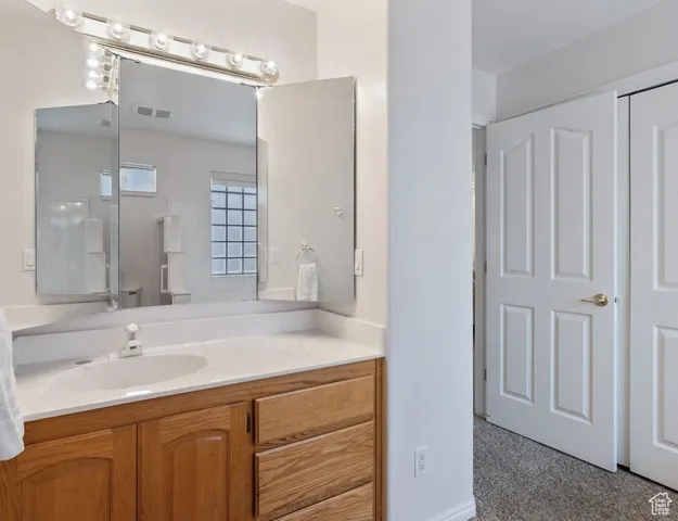 Bathroom featuring vanity and light carpet