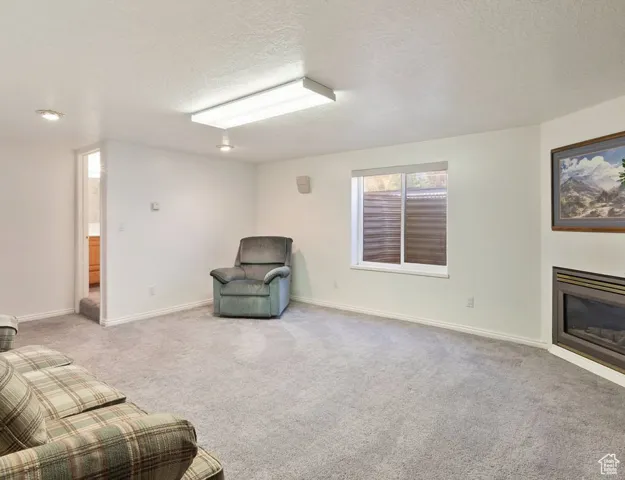 Unfurnished room featuring light carpet, a textured ceiling, and a glass covered fireplace