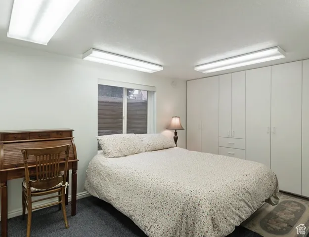 Bedroom featuring a textured ceiling and dark colored carpet