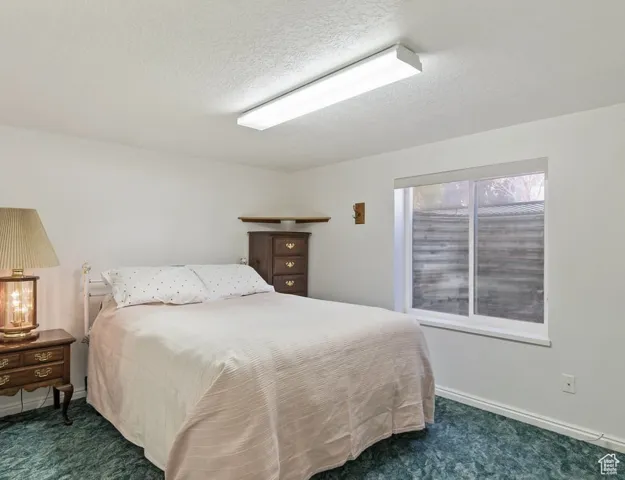 Bedroom with dark carpet and a textured ceiling