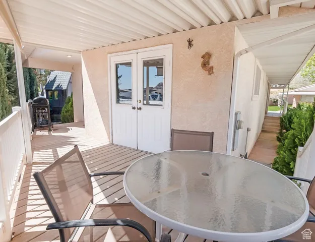 Wooden deck with outdoor dining space, french doors, and a grill
