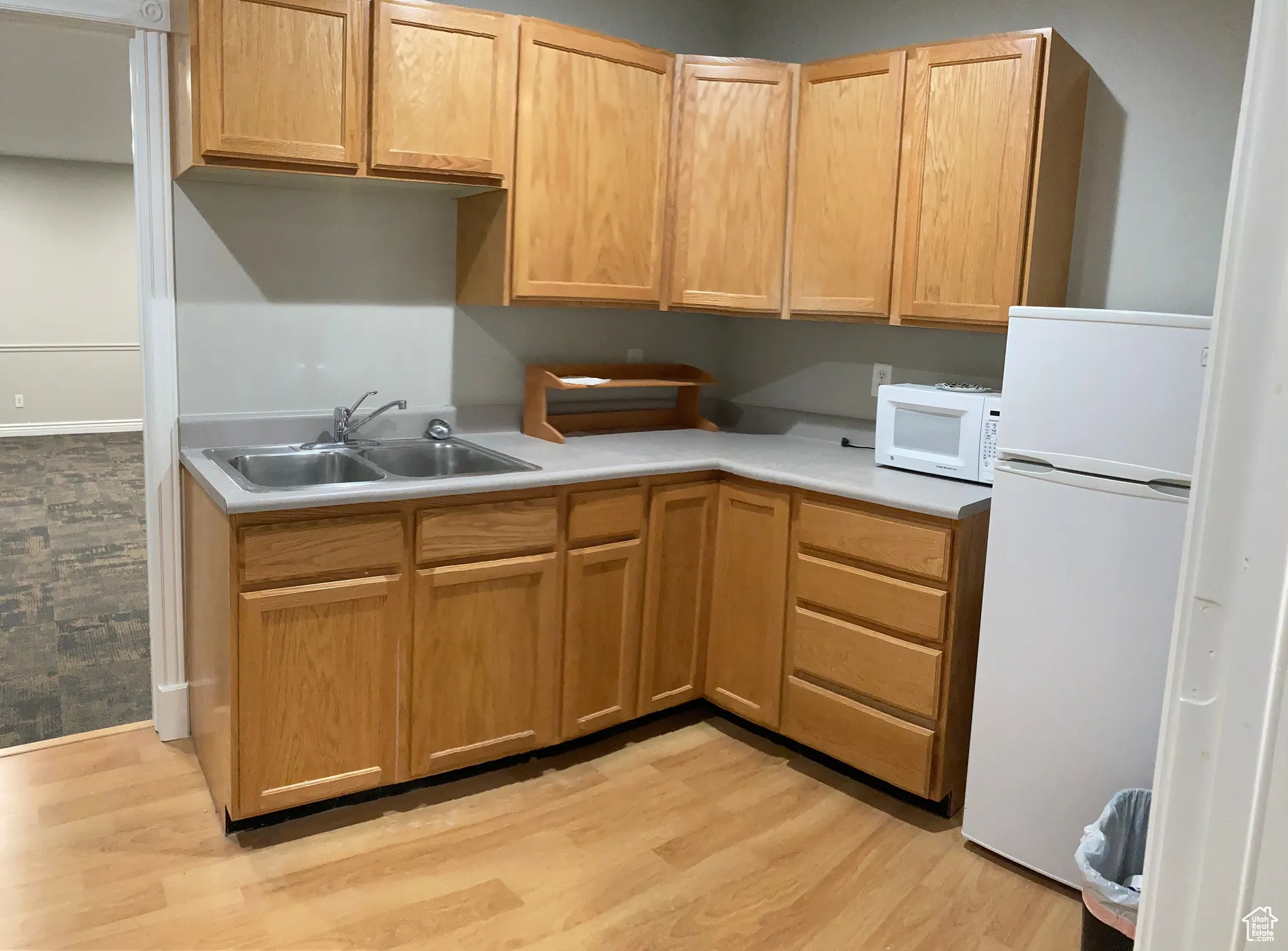 Kitchen featuring light countertops, white appliances, and light wood-style floors