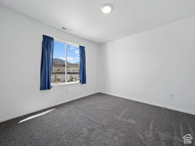 Carpeted spare room featuring baseboards