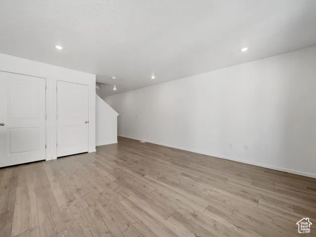 Unfurnished living room with light wood finished floors, recessed lighting, and a textured ceiling