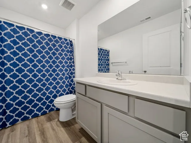 Bathroom with curtained shower, light wood-style flooring, and vanity