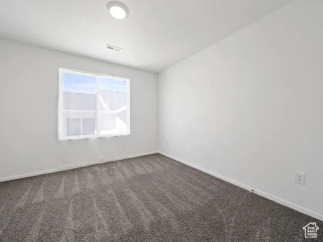 Carpeted spare room featuring baseboards