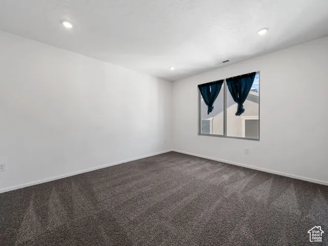 Empty room featuring dark colored carpet and recessed lighting