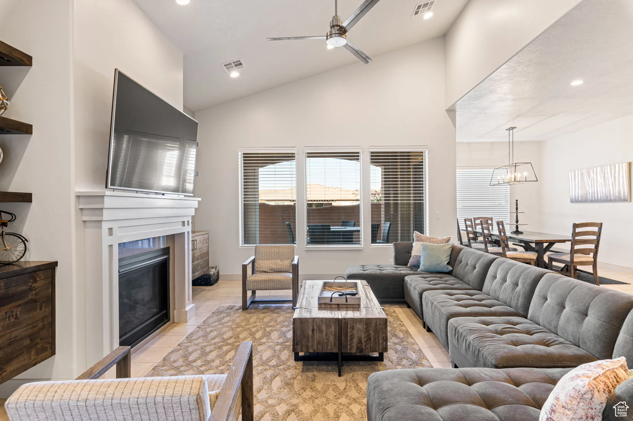 Living area featuring a ceiling fan, recessed lighting, a glass covered fireplace, and high vaulted ceiling