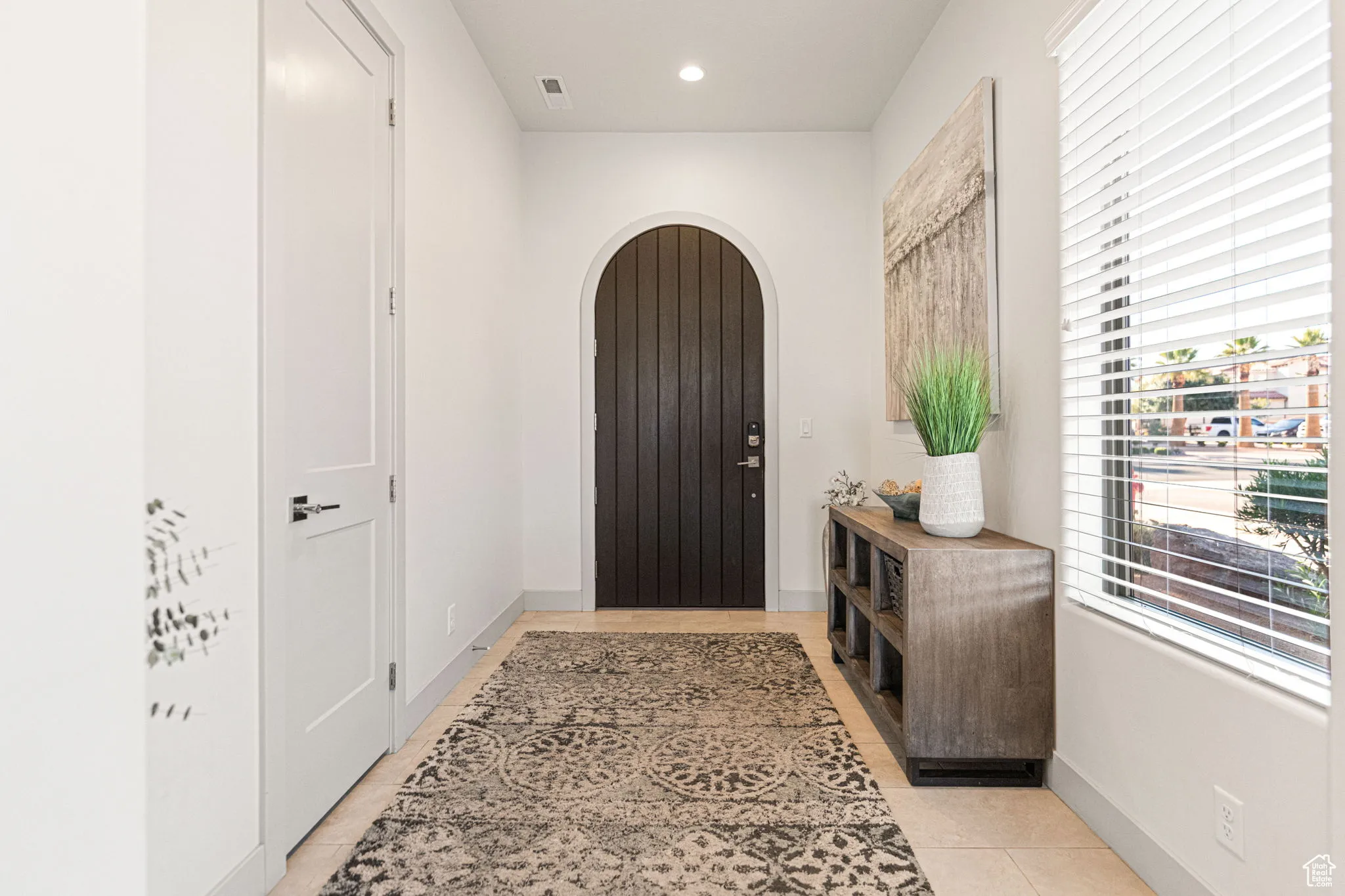 Foyer entrance with arched walkways, light tile patterned flooring, and recessed lighting
