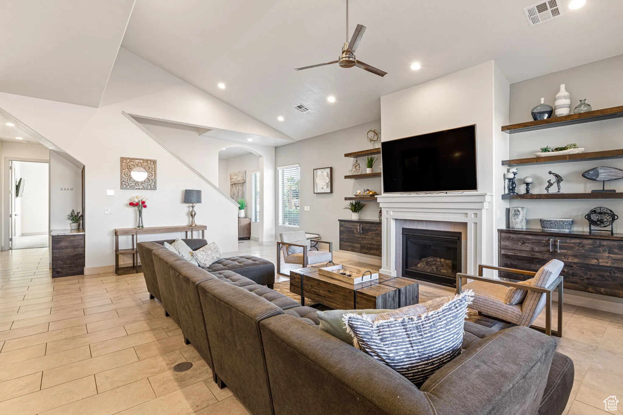 Living room featuring arched walkways, recessed lighting, a glass covered fireplace, ceiling fan, and high vaulted ceiling