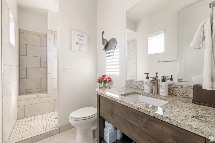 Bathroom featuring light tile patterned floors, vanity, and tiled shower