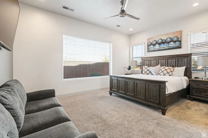 Bedroom featuring light colored carpet, a ceiling fan, and recessed lighting