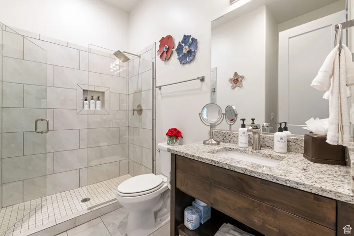 Bathroom featuring vanity, light tile patterned floors, and a stall shower