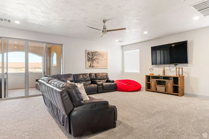 Living area featuring light carpet, a ceiling fan, a textured ceiling, and recessed lighting