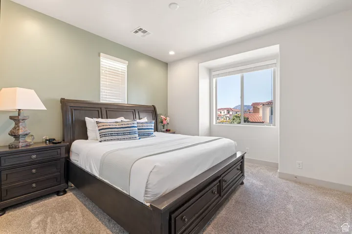 Bedroom with light colored carpet and recessed lighting