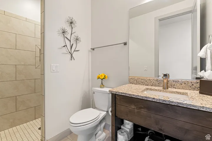 Full bathroom featuring vanity, light tile patterned floors, and a tile shower