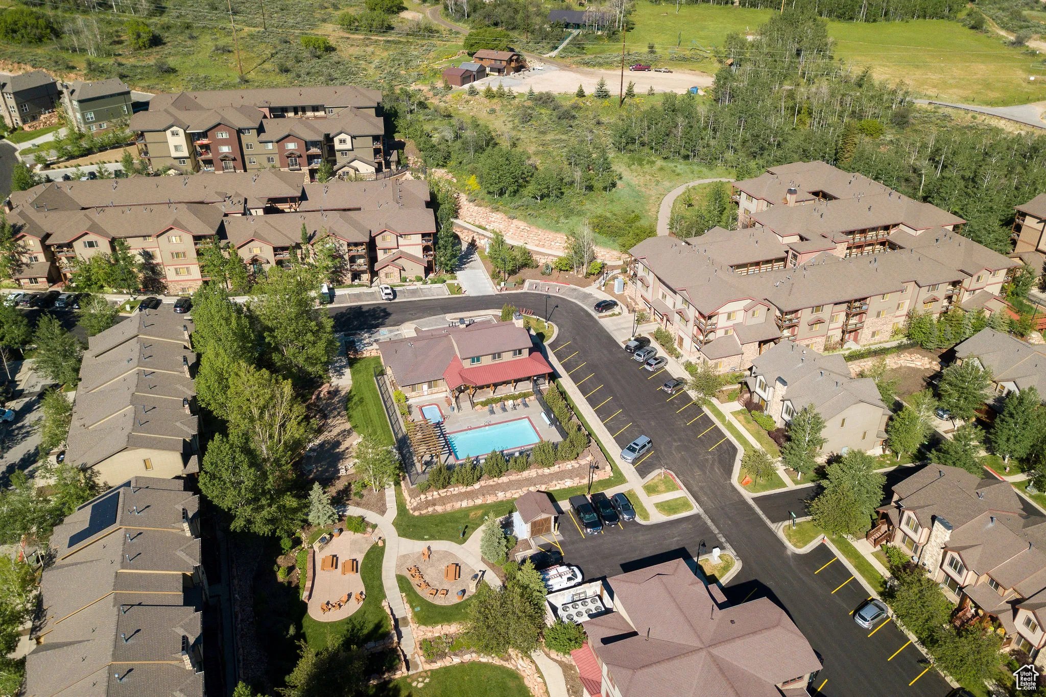 Aerial view of property and surrounding area featuring nearby suburban area and a pool area
