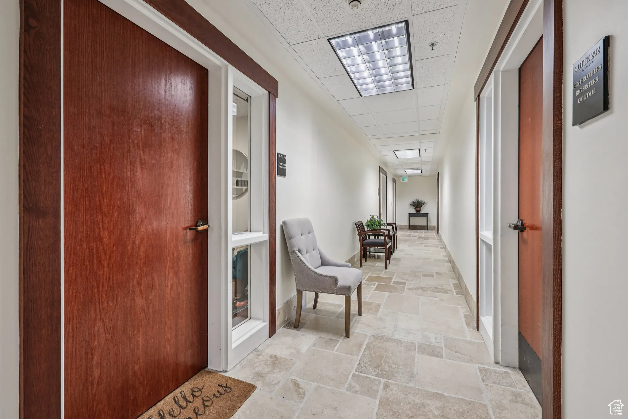 Corridor featuring a paneled ceiling and stone tile floors