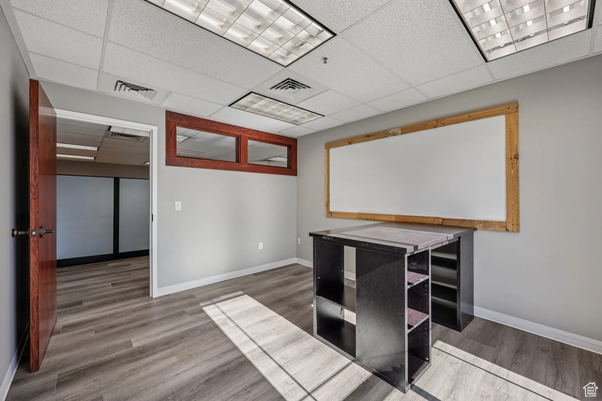 Unfurnished office featuring light wood-style floors and a drop ceiling