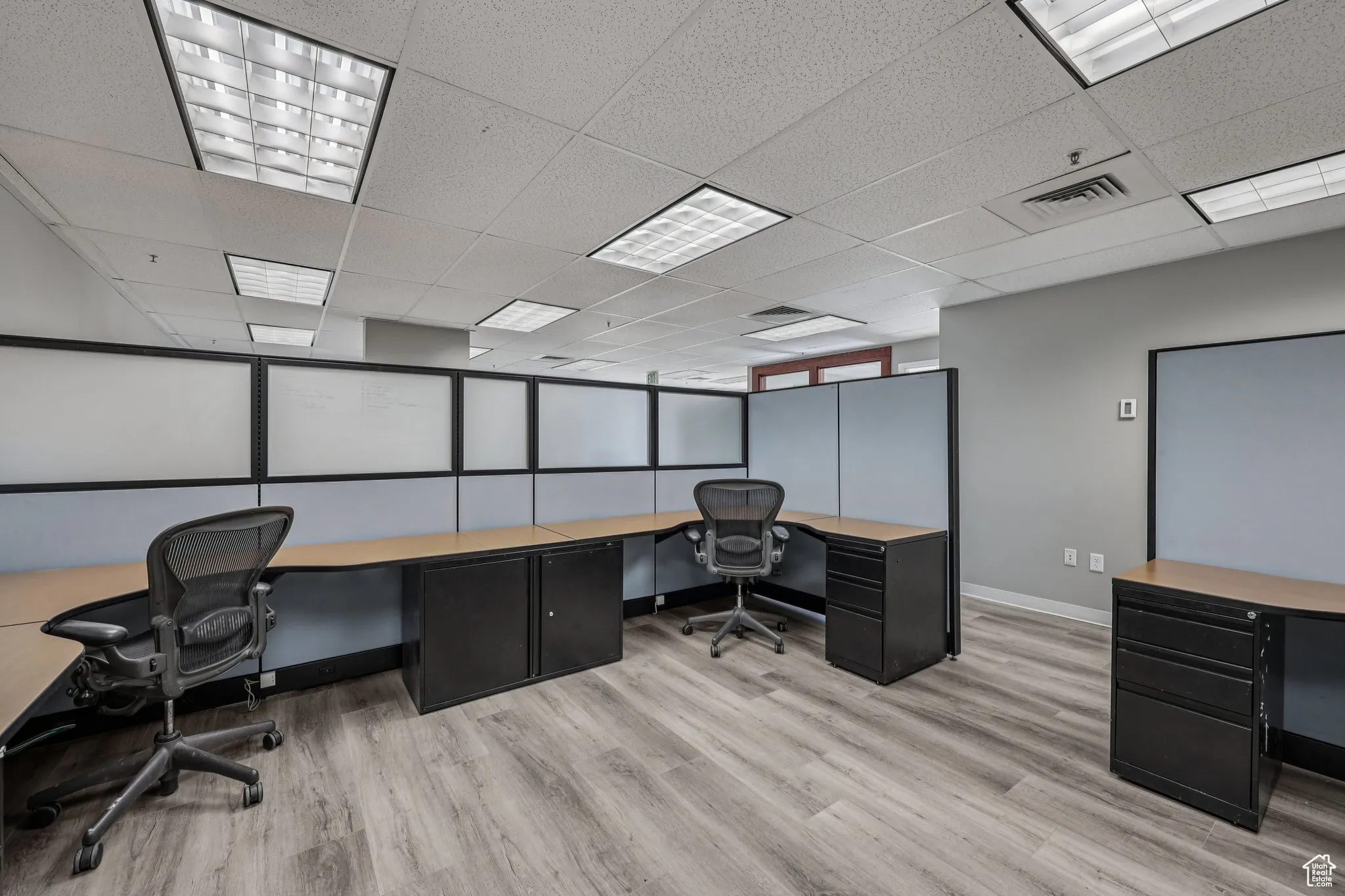 Office area with a drop ceiling and light wood finished floors