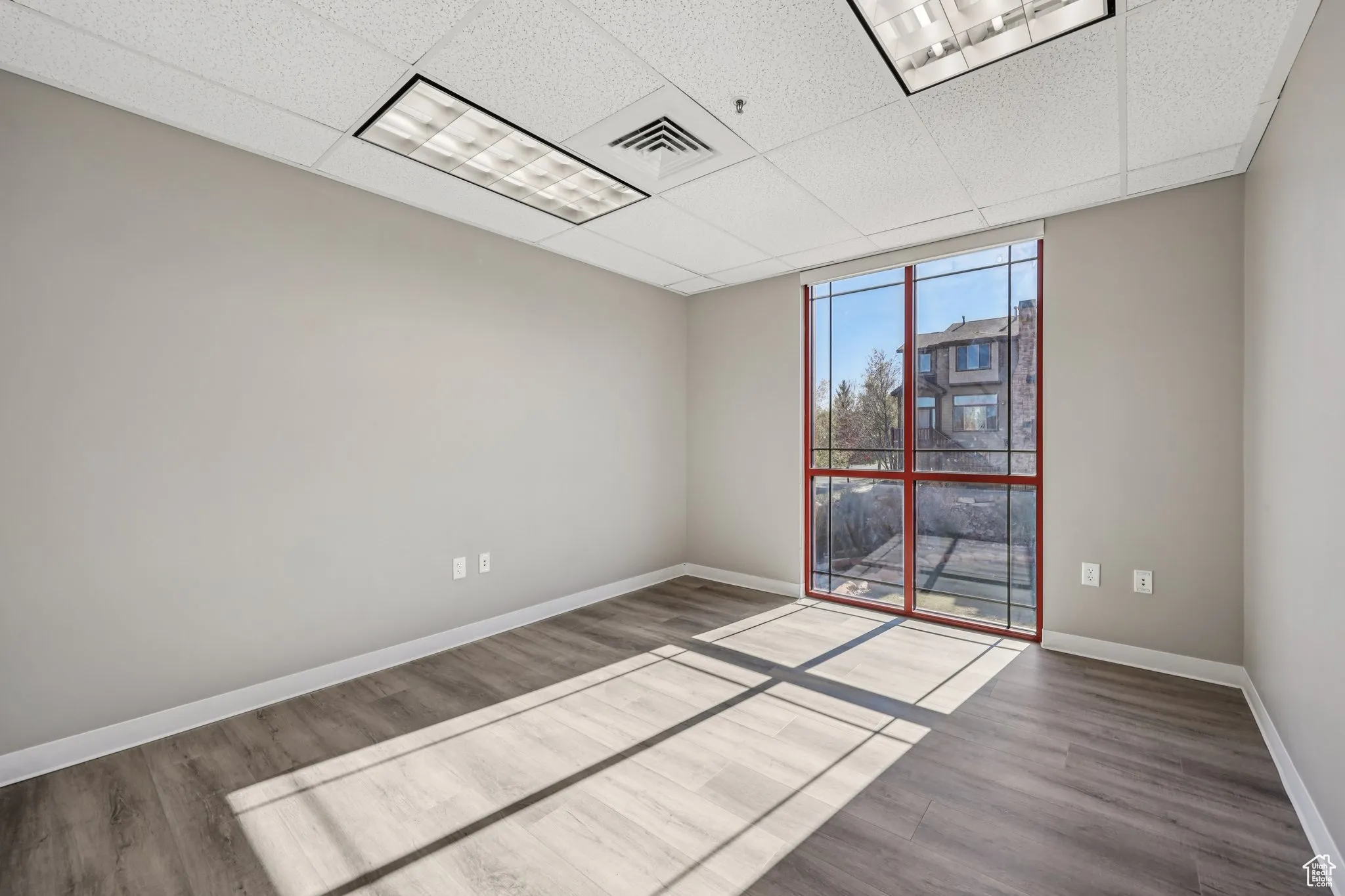 Unfurnished room with a paneled ceiling and wood finished floors