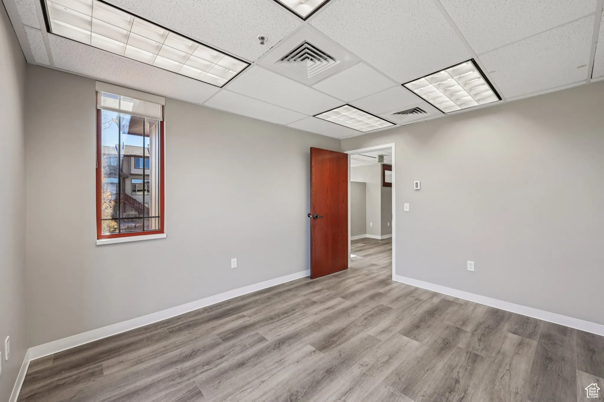 Unfurnished room featuring wood finished floors and a drop ceiling